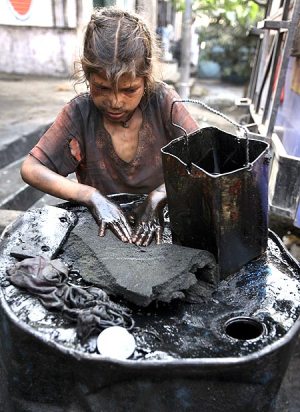 Eight-year-old Gudia, an oil scavenger, collects engine oil at an auto workshop in Jammu.