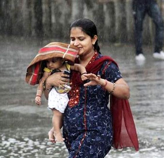 A woman carries her child through a heavy rain shower in Chandigarh. 