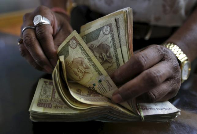 A man counts rupee notes in a bank.