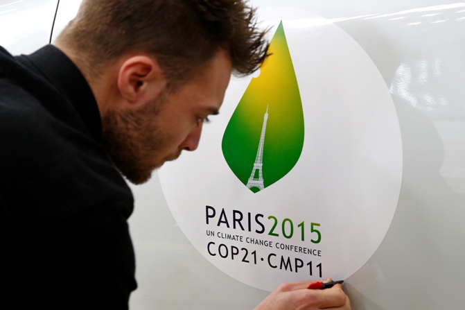 An employee installs a sticker with the logo of the upcoming COP21 Climate Change Conference on a Renault ZOE electric car in Boulogne-Billancourt, near Paris, France, November 16, 2015.