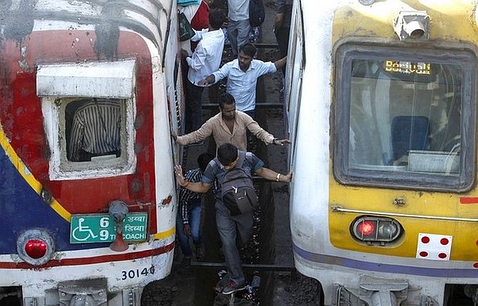Commuters try cross railway tracks as trains wait at a suburban station in Mumbai. 