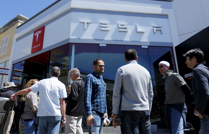 People wait in line at a Tesla Motors dealership to place deposits on the electric car company’s mid-priced Model 3 in La Jolla, California