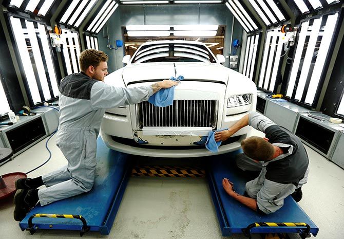 Employees Joe Don (L) and Darren Lowarson give a Rolls Royce Ghost its final finish polish at the Rolls Royce Motor Cars factory at Goodwood near Chichester in southern England