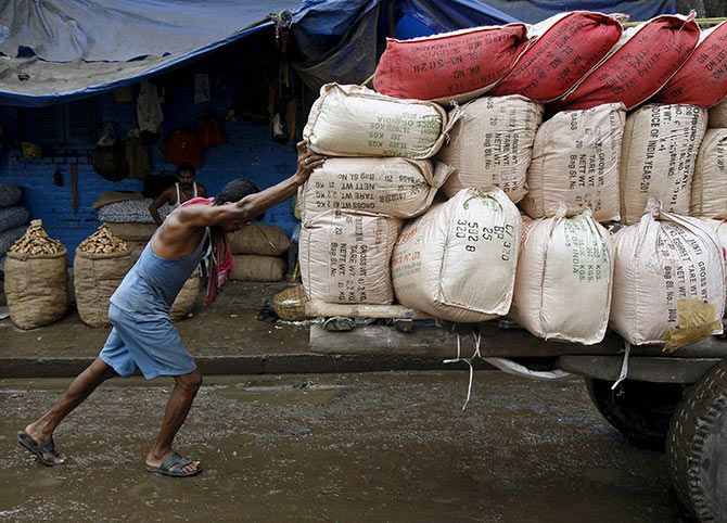 IMAGE: A labourer pushes a handcart loaded with sacks containing tea packets, towards a supply truck at a wholesale market in Kolkata 