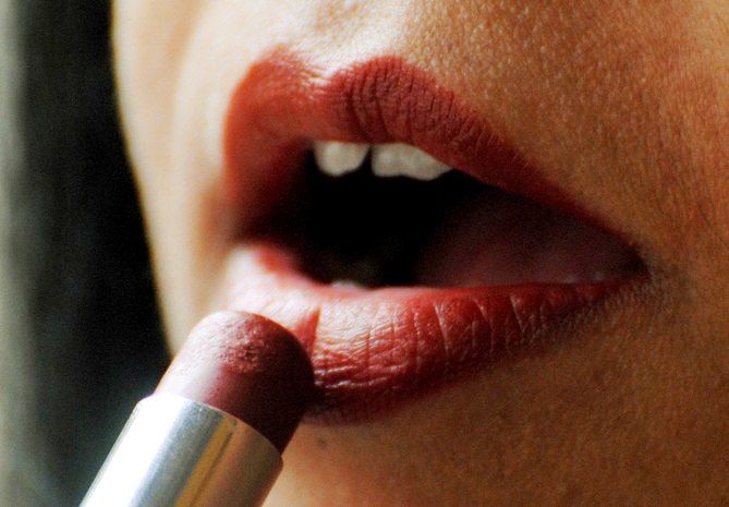 A woman puts on lipstick at a beauty parlour.