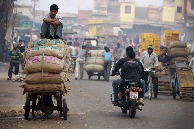 A labourer sits on a pushcart loaded with spices at a busy market in the old quarters of Delhi, India