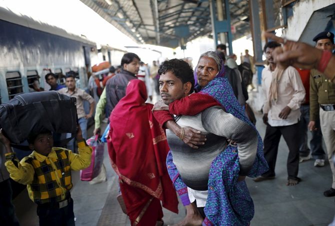 A man carries his mother to board a passenger train at a railway station in New Delhi, February 25, 2016. Photograph: Anindito Mukherjee/Reuters 