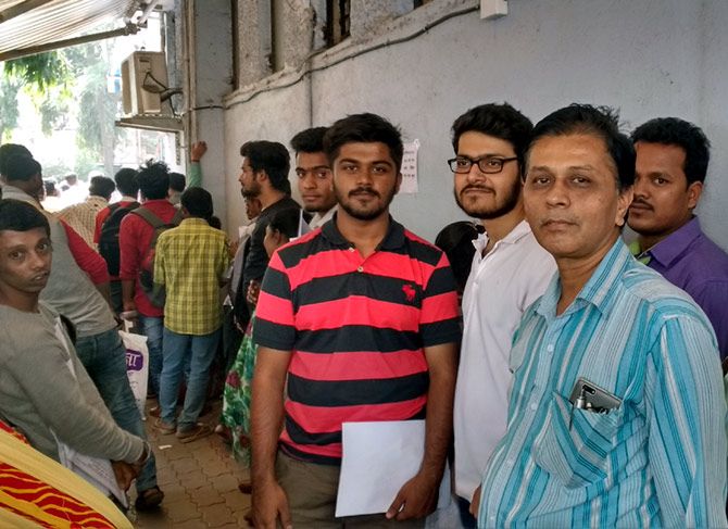 College students Ishit Gangar (in red tee), Harsh Singh (in white tee) and shopkeeper Anil Gandhi (in grey shirt) believe the ban on high-denomination notes will stem the creation of black money.