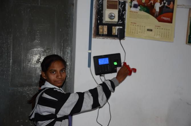 A student at the secondary school demonstrates how they record their attendance using a swipe card