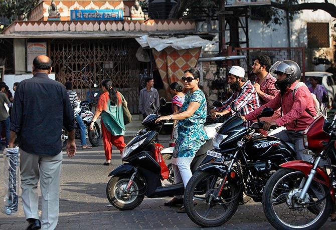 A woman riding a scooter waits for a traffic signal along a street in Mumbai February 5, 2014. 'Plush pink' and 'burgundy bliss' scooters are the new buzz on India's roads, even as the rest of the autos market is sputtering amid an economic slowdown. Young, well-heeled and independent-minded women, who are also conscious of the perils of using public transport, are helping to propel a boom in sales of scooters. Photo: Mansi Thapliyal/Reuters