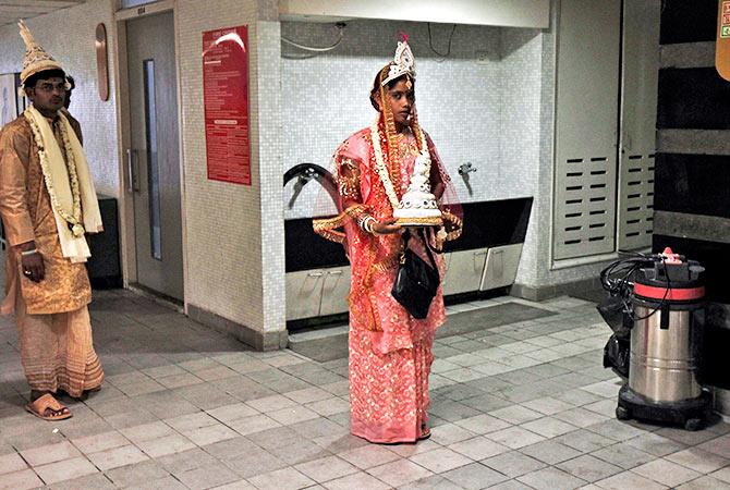 A bride holds the wedding cap of her groom as she waits for him outside a toilet at the venue for a mass marriage ceremony in Kolkata June 18, 2014. Photo: Rupak De Chowdhury/Reuters