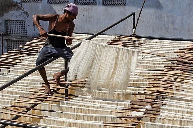 A man hangs strands of vermicelli to dry at a factory in Allahabad, India, June 29, 2016. Photo: Jitendra Prakash/Reuters