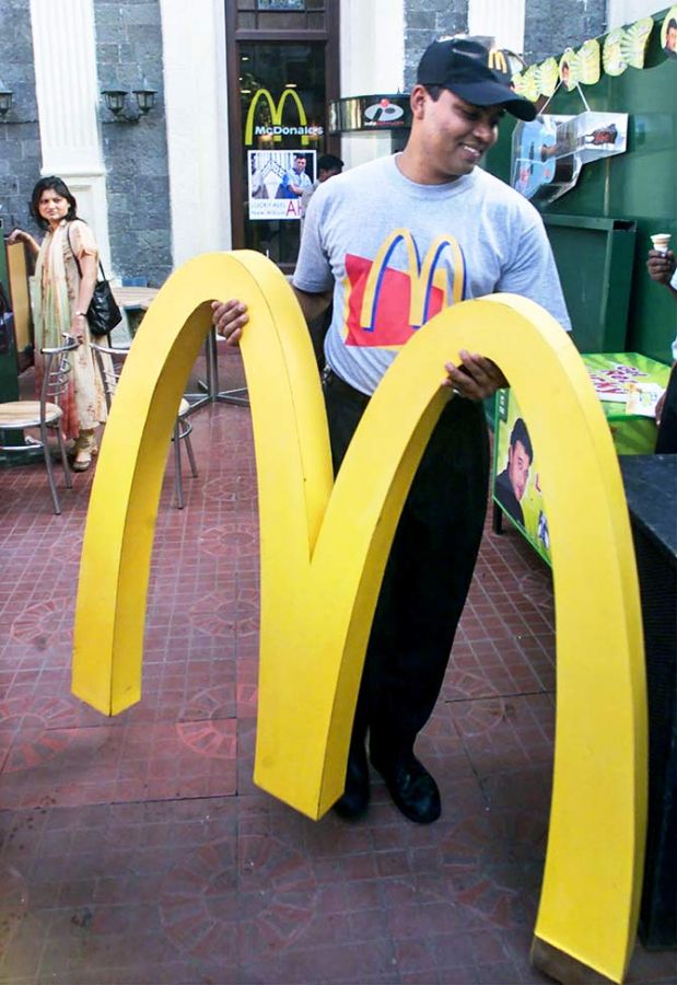 A worker carries the famous golden arches in front of McDonalds restaurant in Bombay. December 5, 2000. Photo: Savita Kirloskar/Reuters