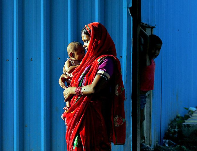 A woman day labourer holds her baby beside a construction site in New Delhi, India July 20, 2017. Photo: Cathal McNaughton/Reuters