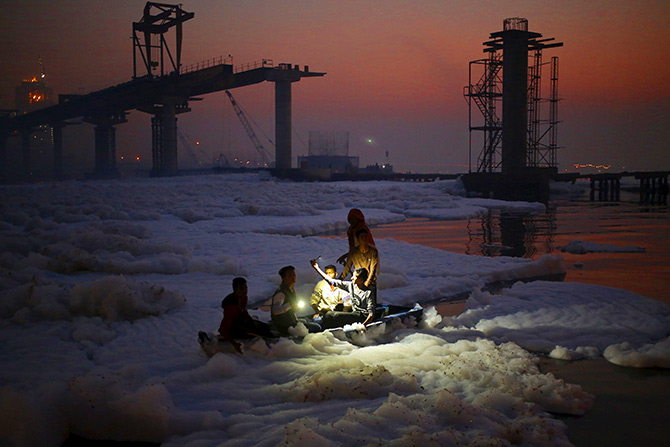 A devotee takes his selfie while sitting on a boat before offering prayers to the rising sun in the polluted waters of Yamuna river during the Hindu religious festival of Chatt Puja in New Delhi, India, November 18, 2015. Women fast for the whole day for the betterment of their families and the society during the festival. Photo: Anindito Mukherjee/Reuters