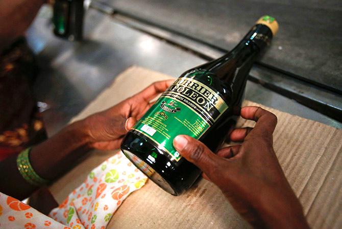 A bottling plant worker affixes a Courrier Napoleon brandy label to a bottle at a Tilaknagar Industries distillery and bottling unit in Srirampur, about 300 km (186 miles) northwest of Mumbai, January 28, 2013. Photo: Vivek Prakash/Reuters