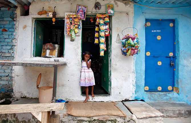 A girl stands at the door of a grocery shop at a slum in New Delhi July 29, 2013. Photo: Anindito Mukherjee/Reuters