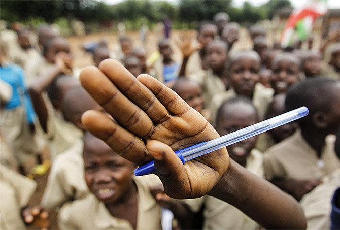 A child holds a pen as children play in the field at the Ave Marie primary school in Bujumbura, Burundi. Photo: Thomas Mukoya/Reuters