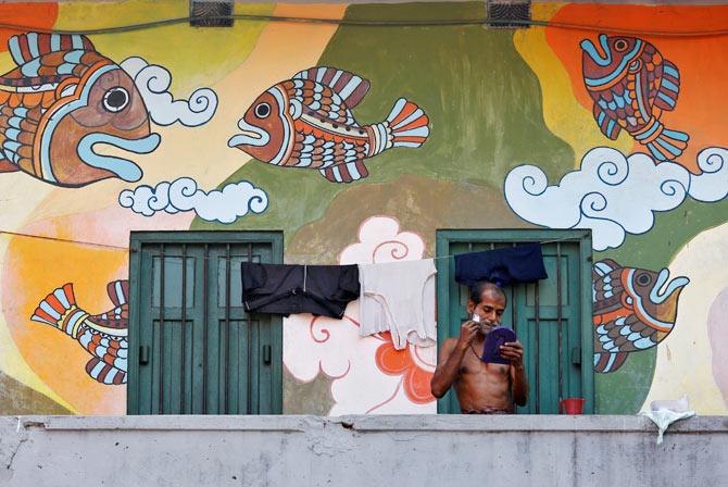 A man shaves his face on the balcony of his home in a market area in Kolkata, India, February 21, 2017. Photo: Rupak De Chowdhuri/Reuters