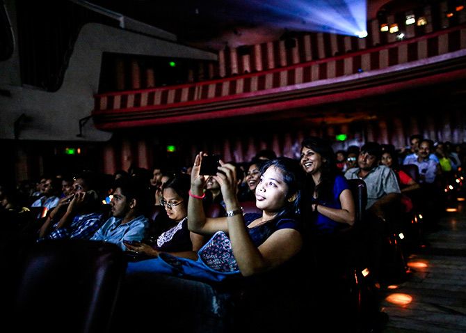 A cinema goer takes a picture as others watch Bollywood movie Dilwale Dulhania Le Jayeng. Photo: Danish Siddiqui/Reuters