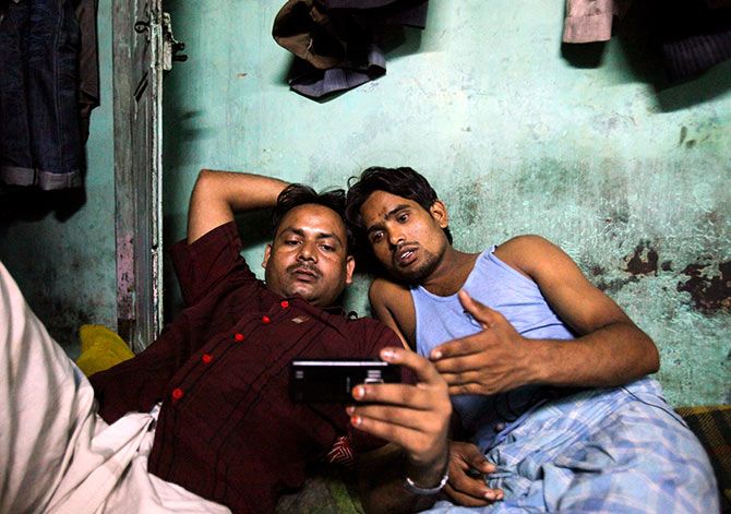 DATE IMPORTED: October 13, 2011 Migrant workers watch movie on a mobile phone in their one room dwelling in a residential area in Mumbai October 3, 2011. Photo: Danish Siddiqui/Reuters