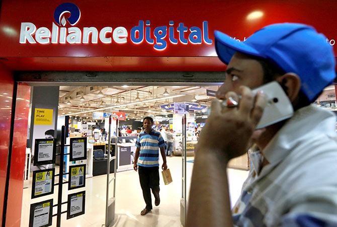 A man speaks on his mobile phone as he moves past a store of Reliance Industries Ltd, controlled by Mukesh Ambani, one of India's richest men, at a shopping mall on the outskirts of Kolkata, India, September 7, 2016. Picture taken September 7, 2016. Photo: Rupak De Chowdhuri/Reuters