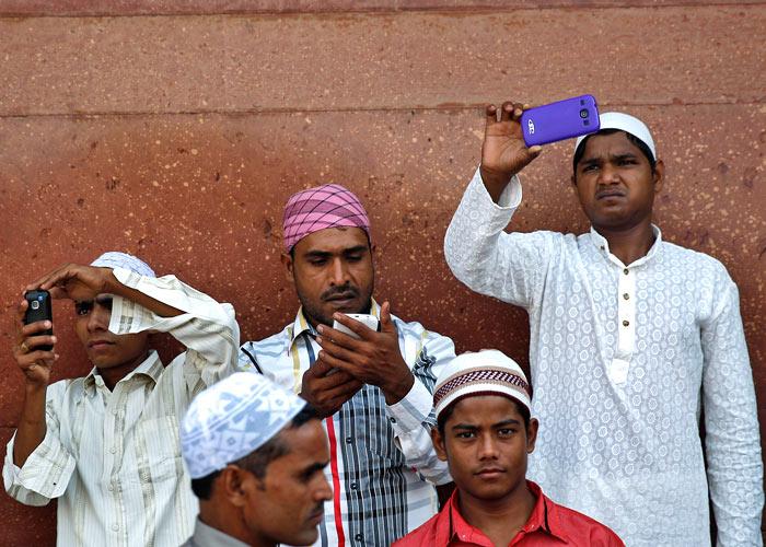 Muslims use their mobile phones after offering Eid al-Adha prayers at the Jama Masjid (Grand Mosque) in the old quarters of Delhi October 6, 2014. Ahmad Masood/Reuters