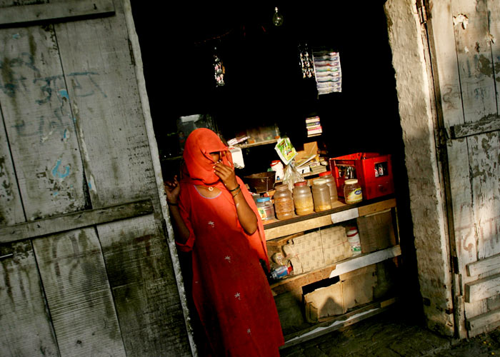 A woman stands outside her shop in the village Hansdehar in the northern Indian state of Haryana July 1, 2006. Hansdehar village has uploaded itself onto the Internet, giving the outside world a glimpse of life in rural India.Photo: Adnan Abidi/Reuters.