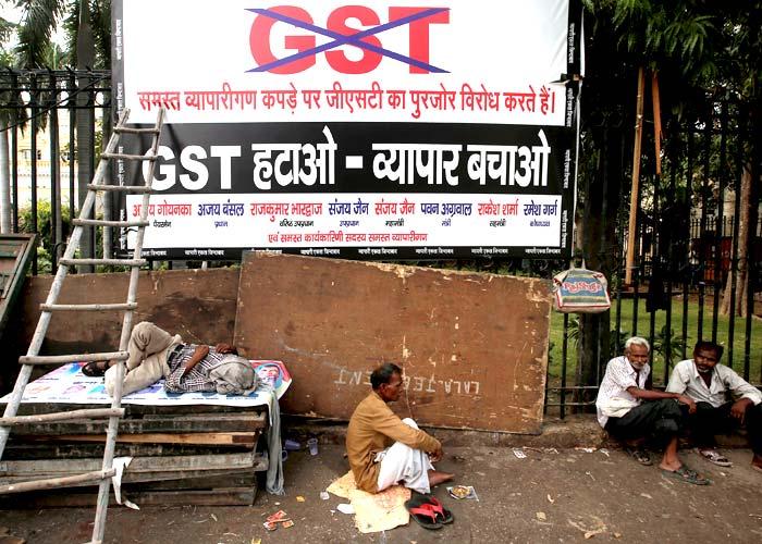 Labourers sit next to a banner after a protest against the implementation of the goods and services tax on textiles, in the old quarters of Delhi, June 29, 2017. Adnan Abidi/Reuters