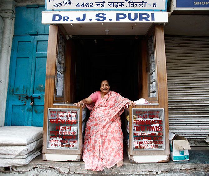 A woman selling tooth powder smiles in her shop in the old quarters of Delhi. Photograph: Mansi Thapliyal/Reuters. 