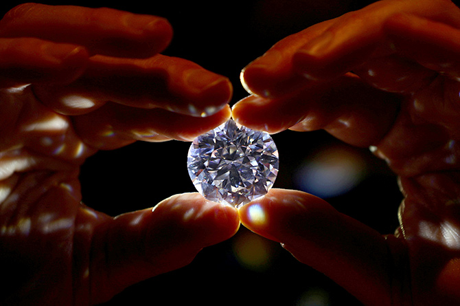 An assistant holds a 102.34 carat white diamond at Sotheby's auction house in London, February 8, 2018. Photograph: Hannah McKay/Reuters.