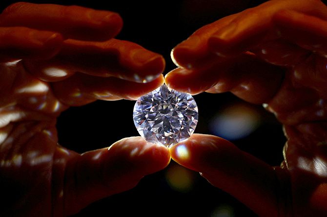 An assistant holds a 102.34 carat white diamond at Sotheby's auction house in London, February 8, 2018. Photograph: Hannah McKay/Reuters.