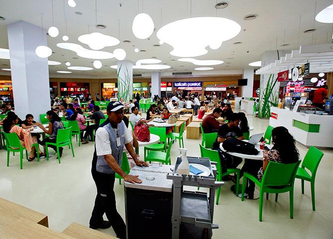 A cleaner pushes a trolley as customers eat at the foodcourt of a shopping mall in Mumbai. Photograph: Vivek Prakash/Reuters