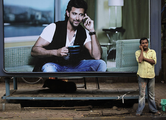 A man makes a phone call on his mobile phone in front of an advertisement for Reliance in Mumbai June 8, 2010. Abu Dhabi's Etisalat is looking at a deal with Reliance Communications as it mulls its options in India, while AT&T Inc denied media reports it was in talks with India's No. 2 mobile player. Photograph: Rupak De Chowdhuri/Reuters.