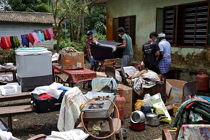 Volunteers collect household items in the lawns of a residential house before cleaning the house following floods in the Kuttanad. Photograph: Sivaram V/Reuters.