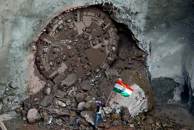 A construction worker waves the India's national flag to celebrate in front of a tunnel boring machine breakthrough point after successfully building a tunnel for the metro train near the Chhatrapati Shivaji Maharaj International Airport, Mumbai. Photograph: Francis Mascarenhas/Reuters