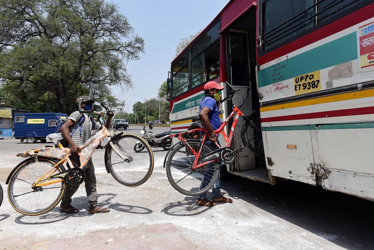 Migrant labour take their bicycles inside a bus as they board it for their native places during the COVID-19 Photograph: ANI Photo