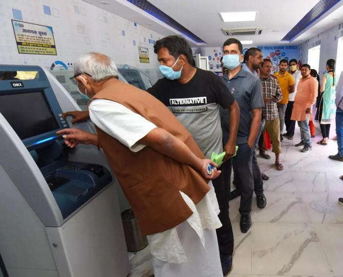 People wait to withdraw cash from an ATM. Photograph: PTI Photo