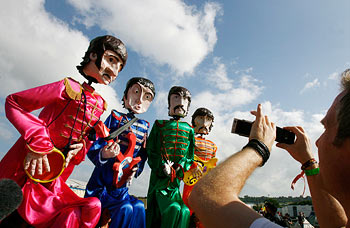 A man photographs giant puppets of Beatles on his mobile phone at Glastonbury Festival in Somerset