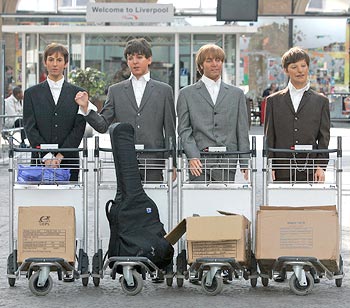 Four wax statues of Beatles pose with luggage trolleys after arriving in Liverpool