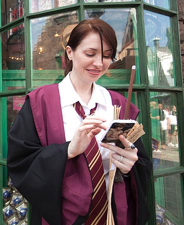 A guest, in her Hogwarts school regalia, uses a mobile phone
