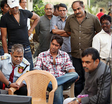 Sanjay Mishra, Ajay Devgn and Paresh Rawal watch the monitor while Ashwini Dhir (standing, second from right), looks on
