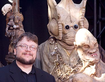Guillermo del Toro poses for photographers surrounded by characters from the movie Hellboy II The Golden Army