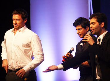 Hugh Jackman seems to adjusts his trousers as Shah Rukh Khan and Karan Johar show him dance moves