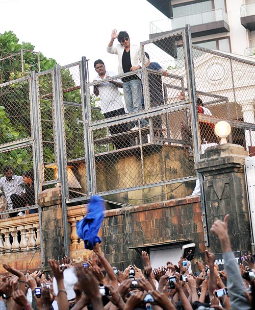 Shah Rukh Khan waves to the crowd gathered in front of his house