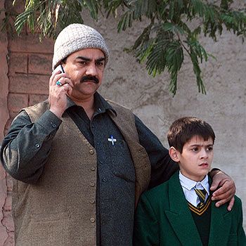 A man talks on a phone, with his arm around a student, outside a military run school that is under attack by Taliban gunmen in Peshawar