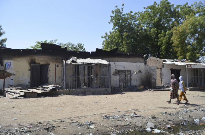 Women walk by homes destroyed by Boko Haram militants in Bama, Borno State