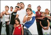 A group of Jewish settlers watches as the Israeli flag is lowered during a farewell ceremony in the Jewish settlement of Nissanit in the nothern Gaza Strip Tuesday August 16.  AP Photo/Tsafrir Abayov 