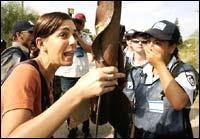 A settler holds a rusted rocket which she said had been fired on the Ganei Tal settlement some time ago as she tries to convince an Israeli police officer to allow settlers to stay in the settlement of Ganei Tal, in the Gush Katif settlement bloc, southern Gaza Strip, Wednesday August 17.AP Photo/Jerry Lampen, Pool