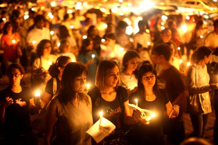 Mumbai residents walk with candles in the street near The Oberoi Hotel